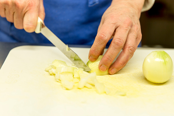 Göttingen, Germany - December, 24: Close up of hands while cutting onion. Volunteers help on Chris...
