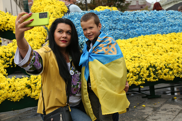 LVIV, UKRAINE - AUGUST 24: A child, wrapped in the Ukrainian national flag, poses with his mother a...
